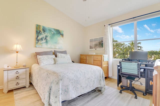 bedroom featuring vaulted ceiling, light hardwood / wood-style floors, and multiple windows