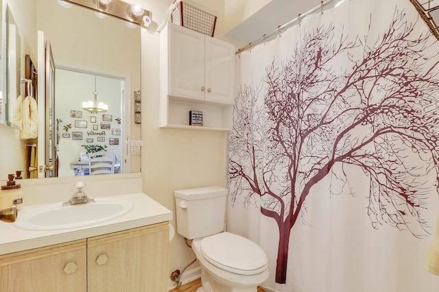 bathroom featuring an inviting chandelier, toilet, and vanity