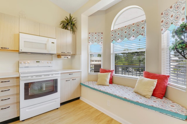 kitchen with a wealth of natural light, light brown cabinetry, white appliances, and light hardwood / wood-style floors