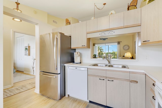 kitchen featuring light brown cabinetry, sink, dishwasher, light wood-type flooring, and stainless steel fridge