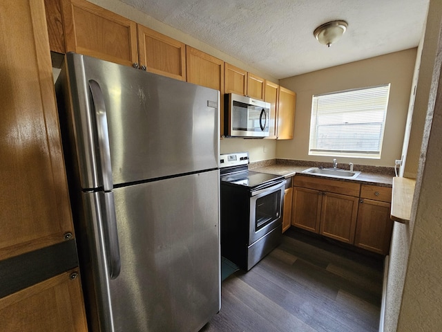 kitchen with sink, stainless steel appliances, dark hardwood / wood-style floors, and a textured ceiling