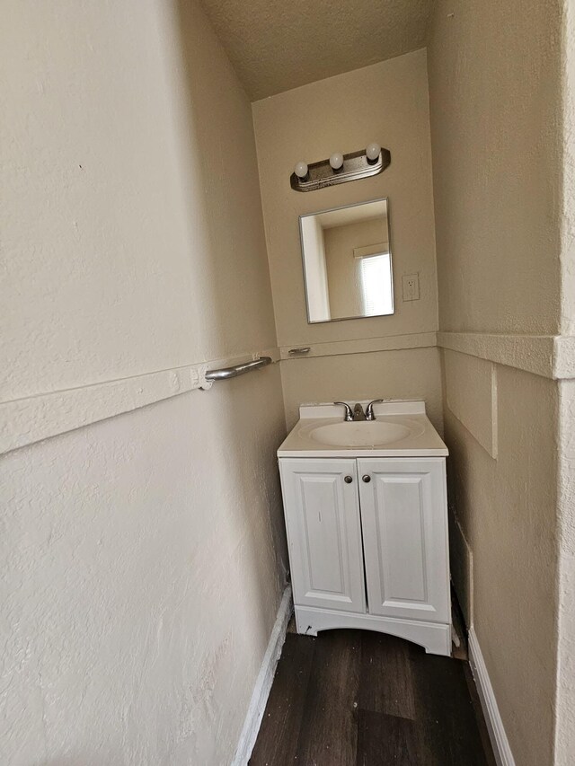 bathroom with lofted ceiling, wood-type flooring, a textured ceiling, and large vanity