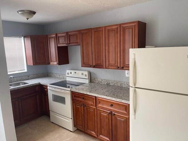 kitchen featuring sink, white appliances, light tile floors, and light stone counters