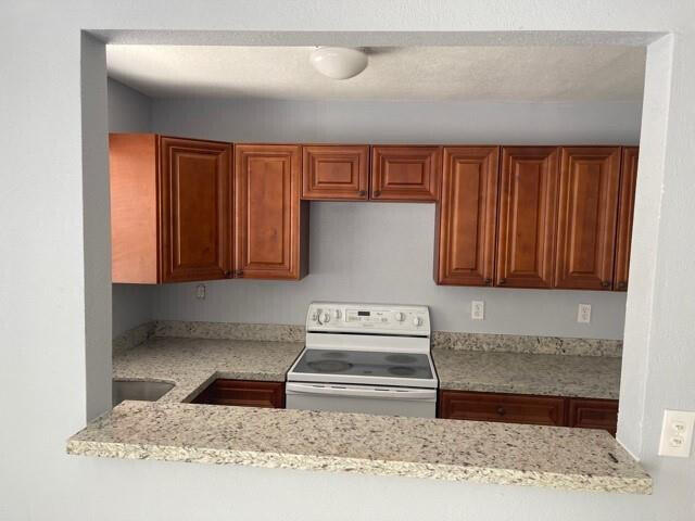 kitchen featuring light stone counters and electric range