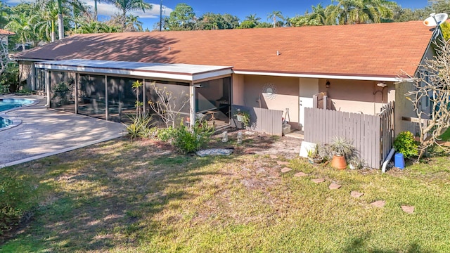 back of property with a yard, a patio area, and a sunroom