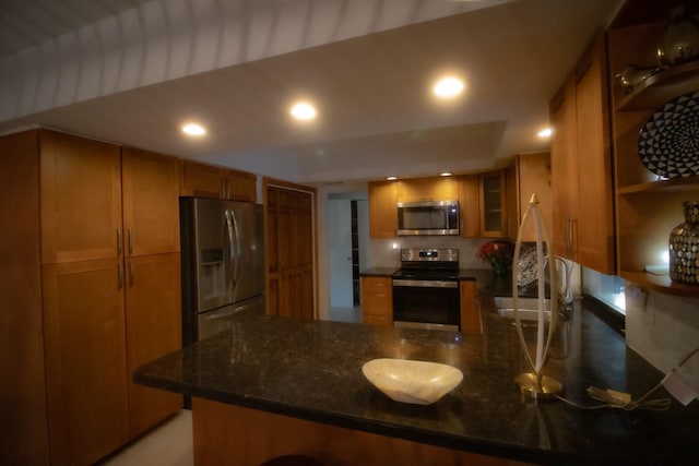 kitchen featuring kitchen peninsula, sink, appliances with stainless steel finishes, and dark stone counters