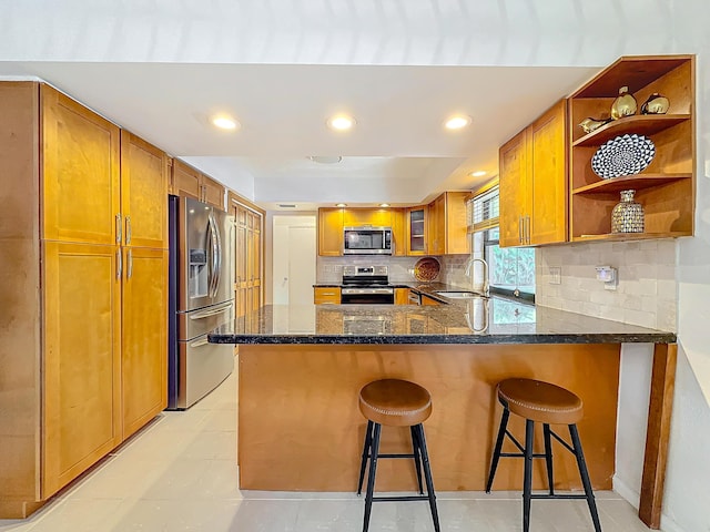 kitchen featuring sink, a kitchen breakfast bar, backsplash, kitchen peninsula, and appliances with stainless steel finishes