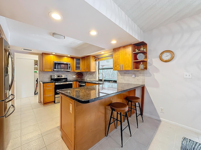 kitchen featuring kitchen peninsula, a kitchen breakfast bar, backsplash, stainless steel appliances, and sink