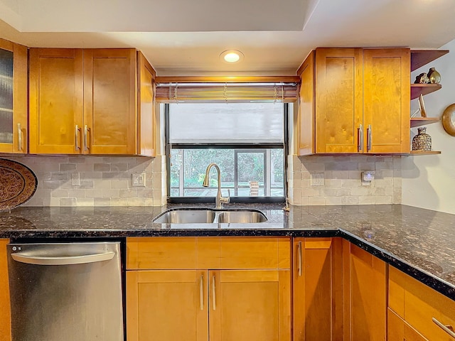 kitchen with stainless steel dishwasher, dark stone countertops, sink, and tasteful backsplash