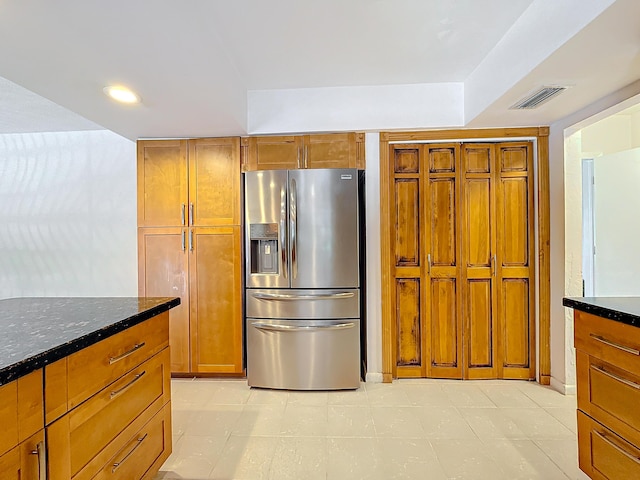 kitchen featuring stainless steel fridge and dark stone counters