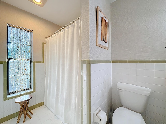 bathroom featuring a shower with shower curtain, tile patterned flooring, toilet, and tile walls