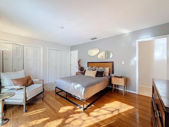 bedroom with multiple closets and wood-type flooring