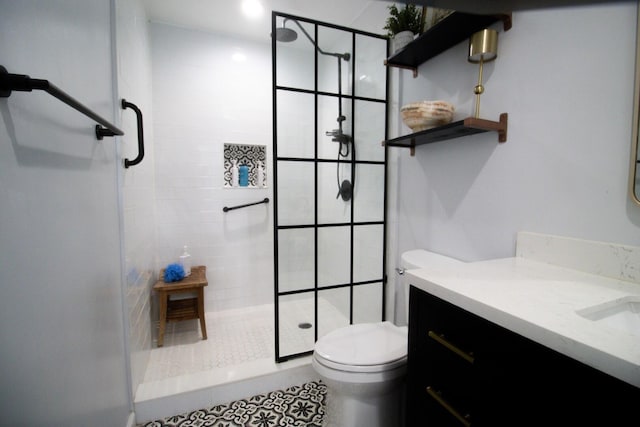 bathroom with tile patterned flooring, vanity, toilet, and a tile shower