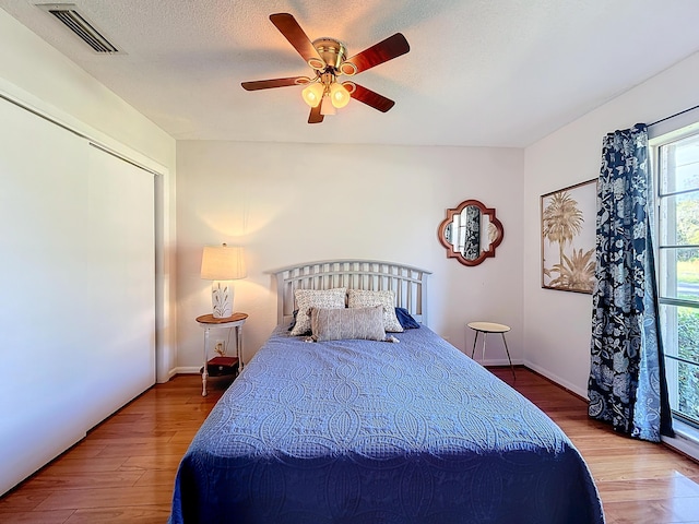 bedroom featuring ceiling fan, a closet, hardwood / wood-style floors, and a textured ceiling