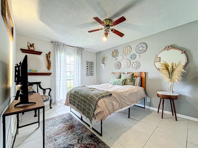 bedroom with ceiling fan, light tile patterned floors, and a textured ceiling