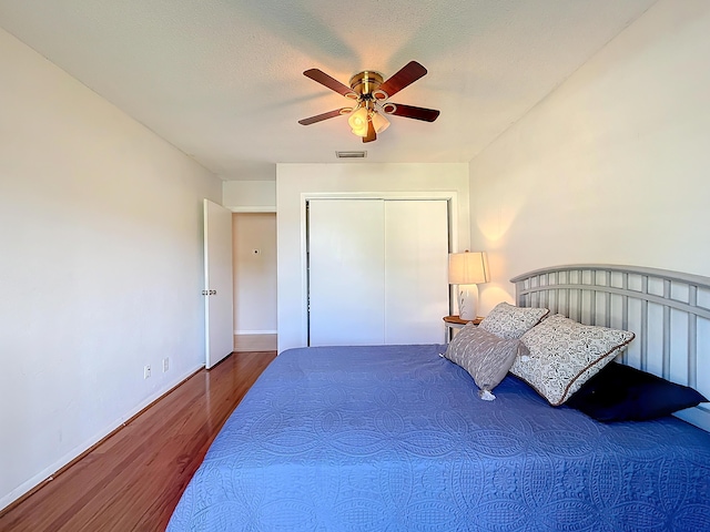 bedroom featuring hardwood / wood-style floors, a textured ceiling, a closet, and ceiling fan