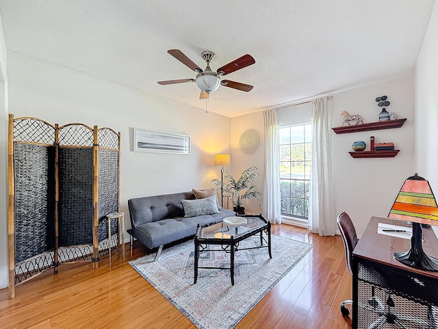 living room with hardwood / wood-style flooring, ceiling fan, and a textured ceiling