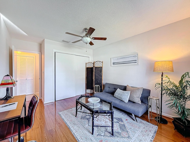 living room with ceiling fan, hardwood / wood-style floors, and a textured ceiling