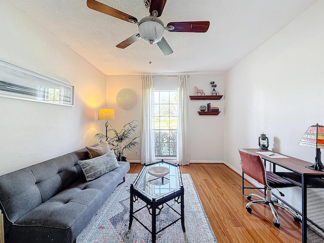 living room with ceiling fan, wood-type flooring, and a textured ceiling