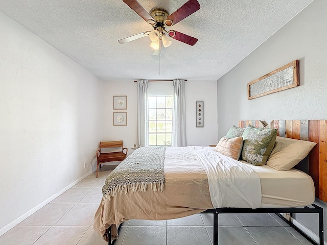 bedroom with ceiling fan, light tile patterned flooring, and a textured ceiling