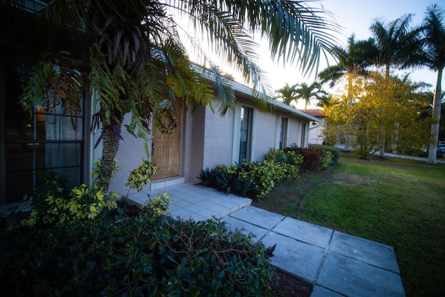 property exterior at dusk featuring a yard