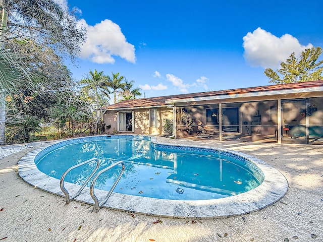 view of swimming pool featuring a sunroom and a patio area