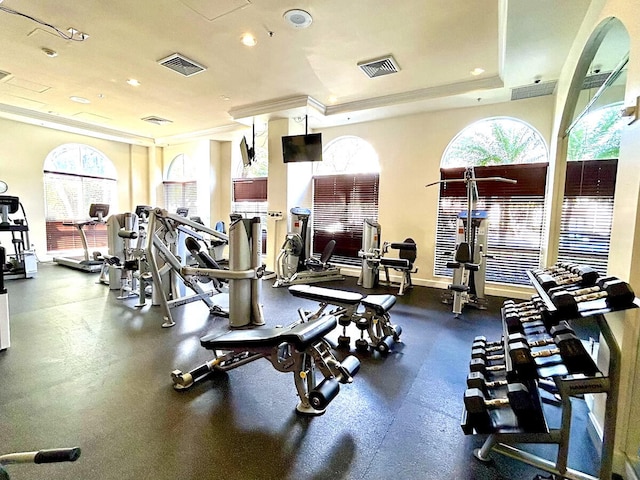 workout area featuring a raised ceiling and ornamental molding