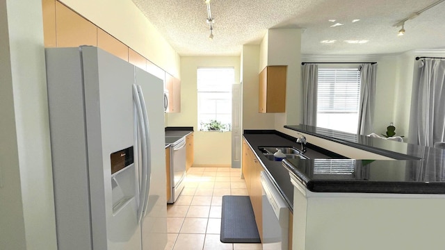 kitchen featuring appliances with stainless steel finishes, a wealth of natural light, sink, and a textured ceiling