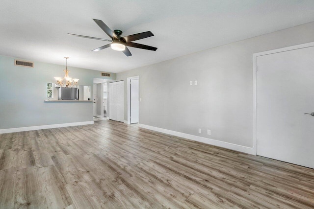 empty room featuring light hardwood / wood-style floors and ceiling fan with notable chandelier