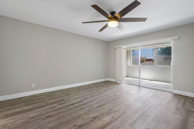 empty room featuring a textured ceiling, ceiling fan, and dark wood-type flooring