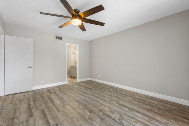 unfurnished bedroom featuring ensuite bath, ceiling fan, and light hardwood / wood-style floors