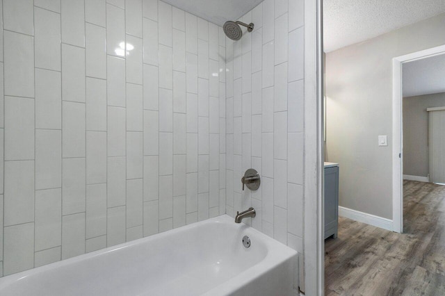 bathroom featuring wood-type flooring, a textured ceiling, vanity, and tiled shower / bath