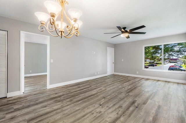 spare room with ceiling fan with notable chandelier and dark hardwood / wood-style flooring