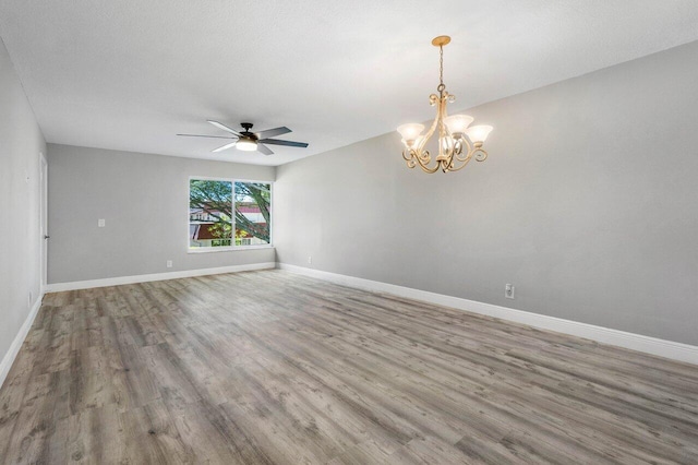 spare room with ceiling fan with notable chandelier and hardwood / wood-style floors