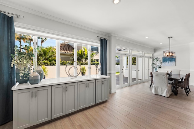 interior space with a healthy amount of sunlight, gray cabinets, light hardwood / wood-style flooring, and decorative light fixtures