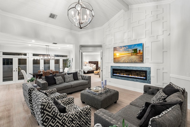 living room with an inviting chandelier, crown molding, and light wood-type flooring