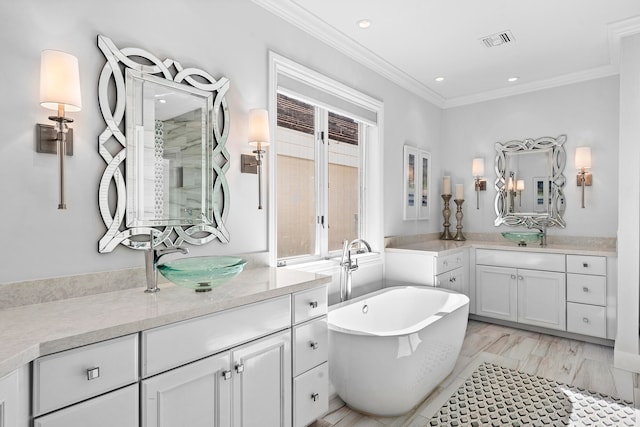 bathroom with ornamental molding, hardwood / wood-style flooring, a bathtub, and dual bowl vanity