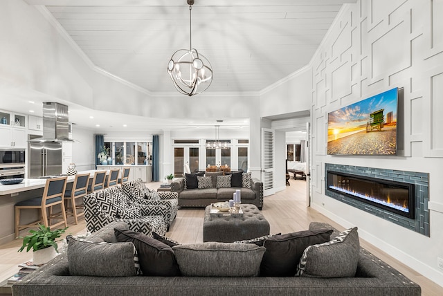 living room featuring crown molding, an inviting chandelier, and light wood-type flooring