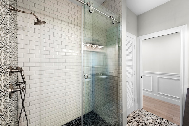 bathroom with wood-type flooring and a shower with shower door