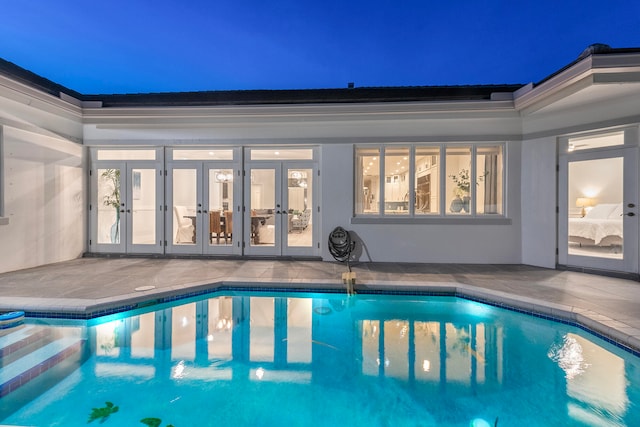 pool at twilight with french doors and a patio