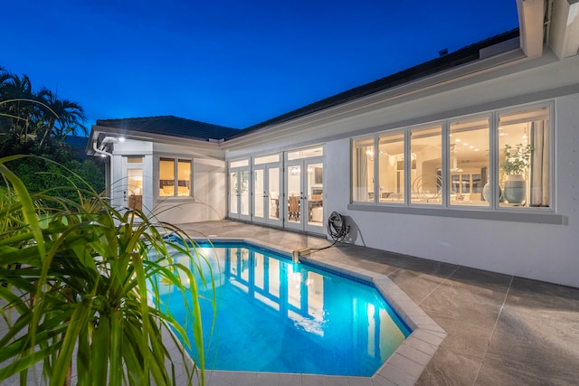 pool at twilight with french doors and a patio