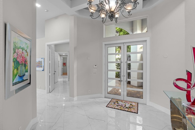 entryway featuring a towering ceiling, a notable chandelier, and french doors