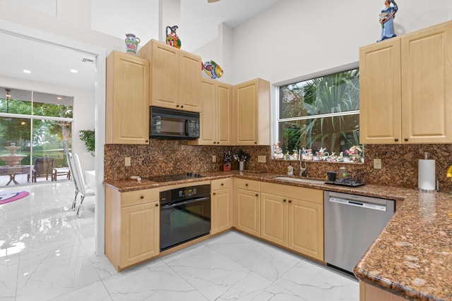 kitchen with dark stone countertops, sink, black appliances, and light brown cabinets