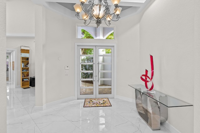 entrance foyer with a towering ceiling, an inviting chandelier, and french doors