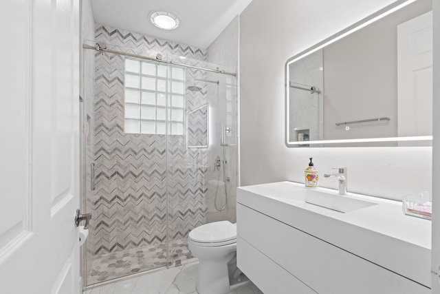 bathroom with vanity, tiled shower, and toilet