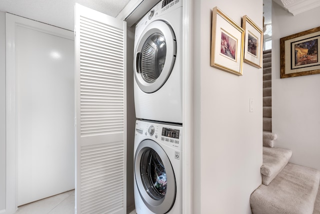 laundry room with light tile floors and stacked washing maching and dryer