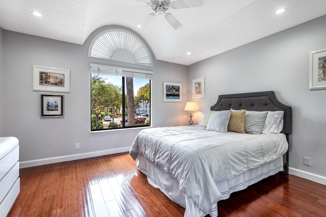 bedroom featuring dark hardwood / wood-style flooring, ceiling fan, and a textured ceiling