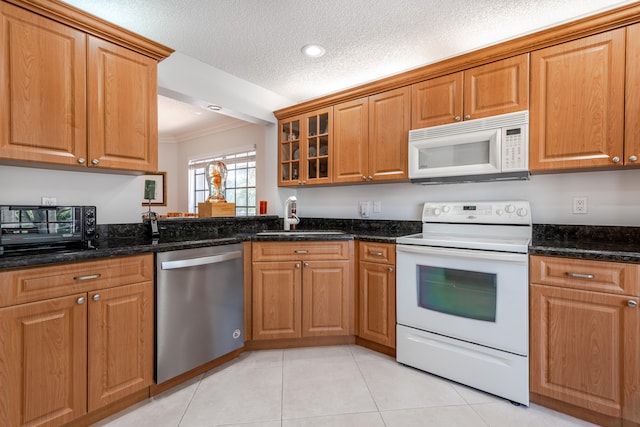 kitchen with dark stone countertops, white appliances, and a textured ceiling