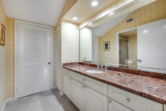 bathroom featuring vanity with extensive cabinet space and lofted ceiling