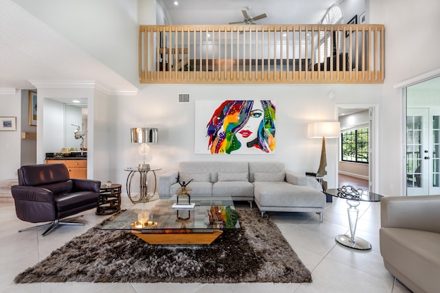 living room featuring crown molding, ceiling fan, light tile floors, and a high ceiling